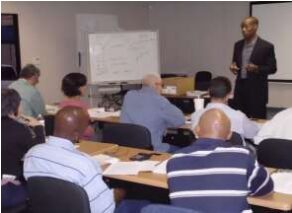 a man speaking Infront of people in a room